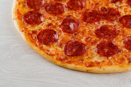 Pizza close-up on white wooden background. Food delivery for people who stay at home. Tasty fast food at quarantine coronavirus covid-19 period.