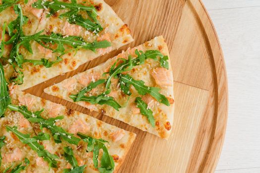 Pizza with salmon, parmesan and arugula isolated on white wooden background. Advert for social network of restaurants, caffee. Promotion for pizzeria.