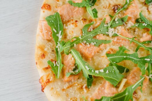 Pizza with salmon, parmesan and arugula isolated on white wooden background. Advert for social network of restaurants, caffee. Promotion for pizzeria.