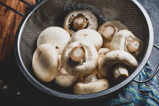 Fresh white button mushrooms in metal colander