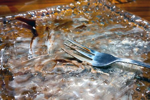 Dirty plate with a fork after taking dessert in a cafe