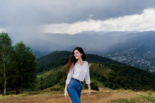 Tourism travelling in Ukraine. Girl enjoying the mountain hills view before rain. Feeling freedom in Karpathian mountains.