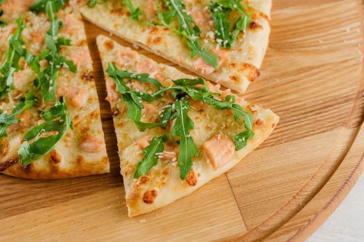 Pizza with salmon, parmesan and arugula isolated on white wooden background. Advert for social network of restaurants, caffee. Promotion for pizzeria.