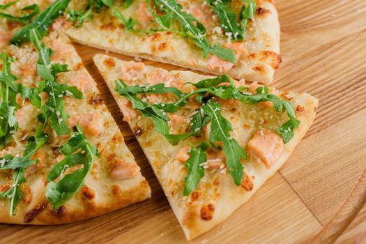 Pizza with salmon, parmesan and arugula isolated on white wooden background. Advert for social network of restaurants, caffee. Promotion for pizzeria.