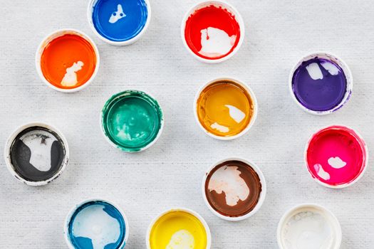 full-frame close-up background of gouache paint jar caps on white cloth background