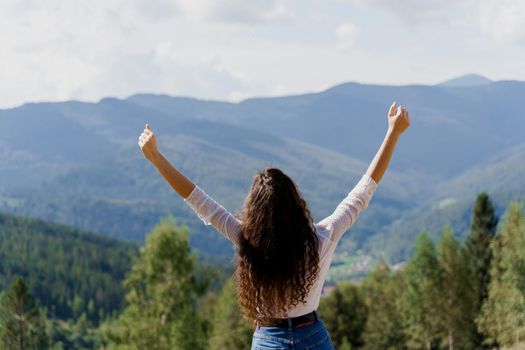 Tourism travelling in Ukraine. Girl girl raised her hands up and enjoys the mountain hills view. Feeling freedom in Karpathian mountains.