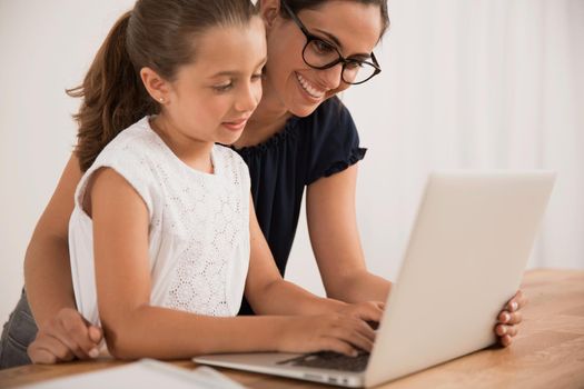 Young mother helping her daughter with homework at home