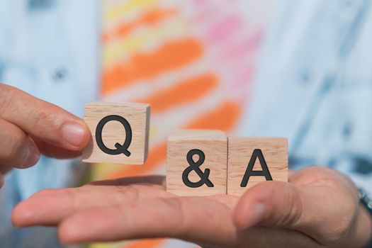 Q and A alphabet on wooden cube in hand hold with background. Question and answer meaning concept.