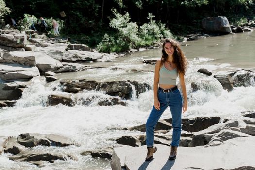 Waterfall in mountain river. Girl is travelling in Karpathian mountains and feeling freedom. Cascade waterfall and beautiful young woman