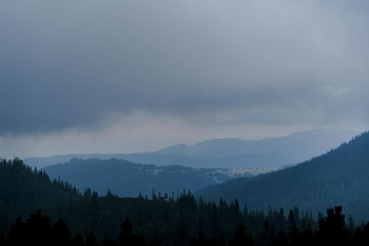 Dusk in the mountains before a storm and a thunderstorm on a rainy and foggy day. Severe weather conditions. Peaks of the Carpathian Mountains