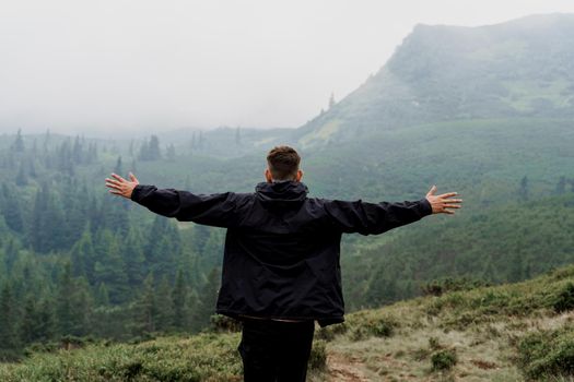 Feeling freedom. Tourist is raised his hands to the side. Hiking and climbing up to the top of the mountain