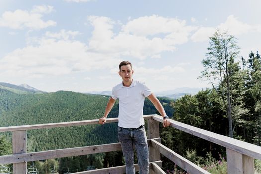 Men traveler is smiling and posing on the green hills background. Advert for travel agency. Tourism. Travelling in the mountains.