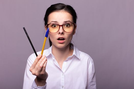 woman in a white shirt and glasses holds a pen . High quality photo