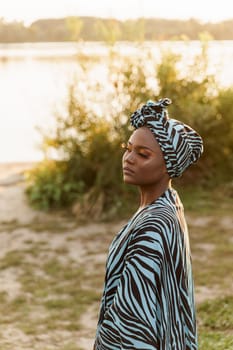 Confident muslim black girl weared in hijab smiles. African woman in national colorful dress on green background. Lifestyle of black girl.