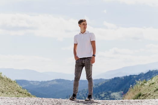 Handsome man is walking on the green hills background. Advert for travel agency. Tourism. Travelling in the mountains.