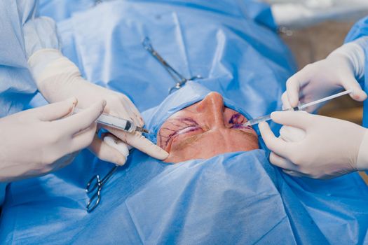 Close-up anesthesia before blepharoplasty and lipofilling plastic surgery operation for modifying the eye region of the face in medical clinic