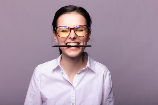 woman in a white shirt and glasses holds a pen with her mouth. High quality photo
