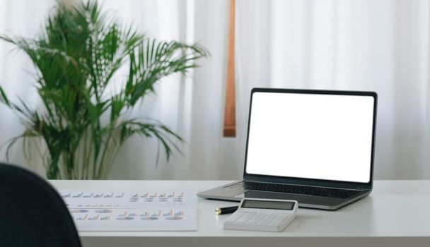 Mockup blank screen laptop on desk. Workspace with laptop and office supplies..