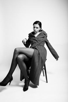 beautiful woman in a coat sits on a chair. High quality photo