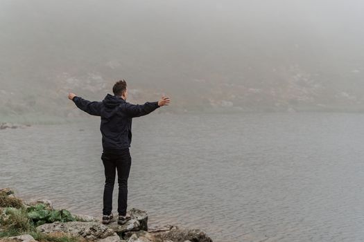 Feeling freedom. Tourist is raised his hands to the side. Hiking and climbing up to the top of the mountain