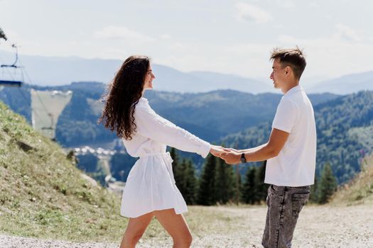 Love story of couple in the mountains. Life style of happy men and woman on the green hills background. Advert for travelling agency. Tourism