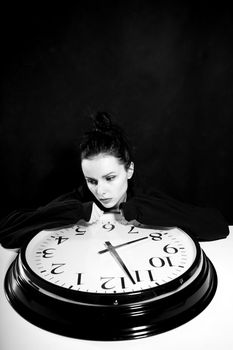 sad woman with big clock, black background. High quality photo