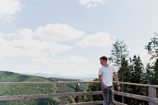 Men traveler is smiling and posing on the green hills background. Advert for travel agency. Tourism. Travelling in the mountains.