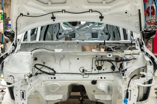 New white car with open hood at a factory