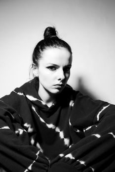 beautiful brunette girl in a black hoodie, light background. High quality photo