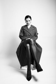 beautiful woman in a coat sits on a chair. High quality photo