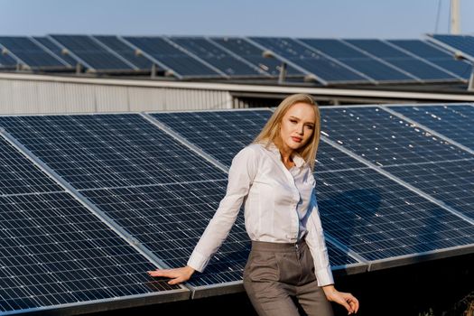 Girl and solar panels stands in row on the ground at sunset. Free electricity for home. Green energy. Solar cells power plant for business