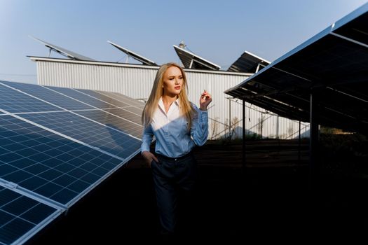 Girl walks between 2 Solar panels row on the ground at sunset. Free electricity for home. Sustainability of planet. Green energy.