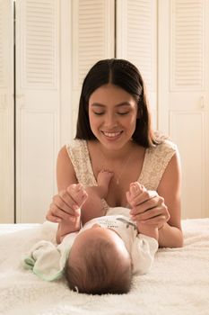Latin young mother love play happy with baby on the bed at home. High quality photo vertical photo style life