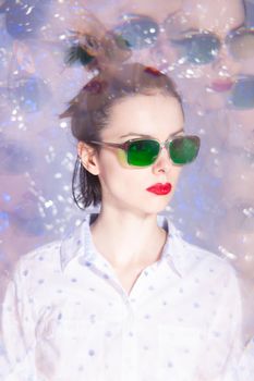 art portrait of a woman in green glasses with red lipstick on her lips in a white shirt. High quality photo