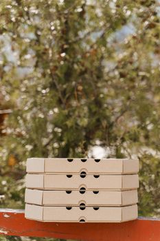 Promotion of 2+2 pizza boxes for food delivery. Isolated vertical photo of 4 cardboard pizza boxes with empty place in upside for text