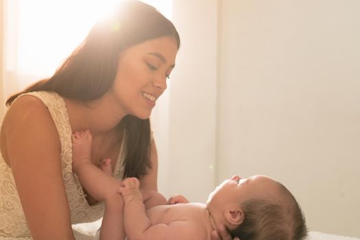 Latin young mother love play happy with baby on the bed at home. High quality photo horizontal photo style life