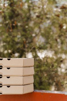 Promotion of 2+2 pizza boxes for food delivery. Isolated vertical photo of 4 cardboard pizza boxes. Safery courier delivery from restaurant