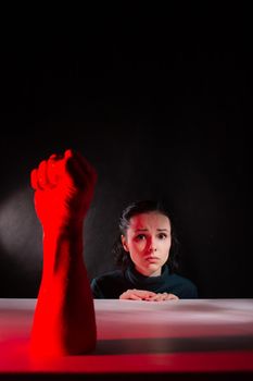 woman afraid of red hand, symbol of dictatorship, black background. High quality photo