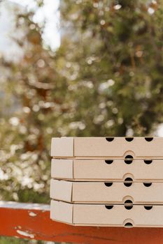 Promotion of 2+2 pizza boxes for food delivery. Isolated vertical photo of 4 cardboard pizza boxes. Safery courier delivery from restaurant