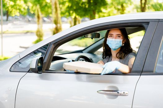 Pretty young girl seats in car and gets georgian cheese pastry from courier. Woman in medical mask and gloves. Georgian hot food delivery