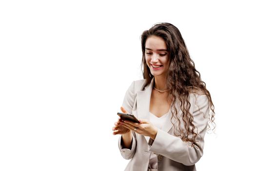 Girl is serfing on the internet using smartphone. Manager works on-line by phone. Attractive girl with curly hair holds phone in hands.