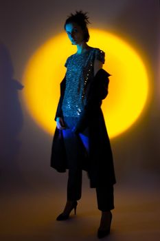 a woman in a black leather coat, in high-heeled shoes illuminated by colored light. High quality photo