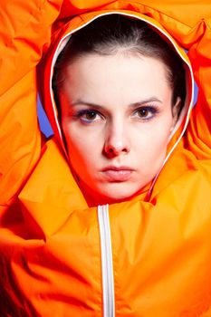 brunette woman in orange jacket, blue background. High quality photo