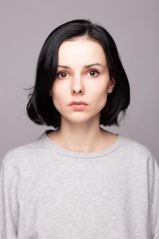 emotional woman in a gray sweatshirt, gray background. High quality photo