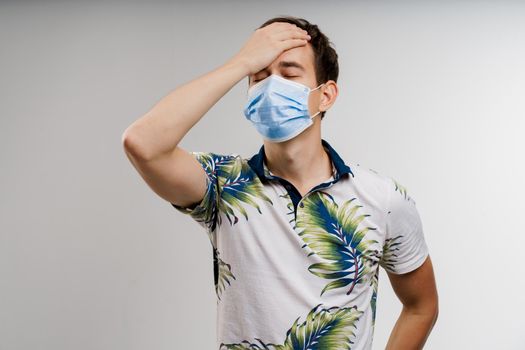 Headache man in blue medical mask isolated white background. Man touches her head because sicks coronavirus covid-19. Pandemic 2020.