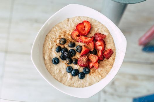 Homemade oatmeal with blueberries and strawberries in a bowl. Healthy breakfast. Top view