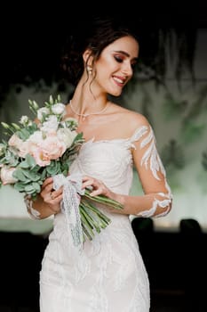 Bride with wedding bouquet smiles and touches her face. Attractive girl portrait for social networks. Girl in wedding dress in luxury restaurant.