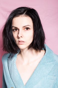 portrait of a brunette woman in a blue velvet jacket on a pink background. High quality photo