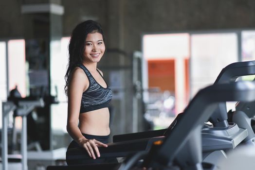 Asian sport woman running on treadmill in fitness club. Cardio workout. Healthy lifestyle, guy training in gym. Sport running concept
