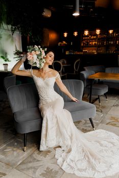 Bride in wedding dress and bridal veil seats on fashion chair in cafe. Advert for social networks for wedding agency and bridal salon.